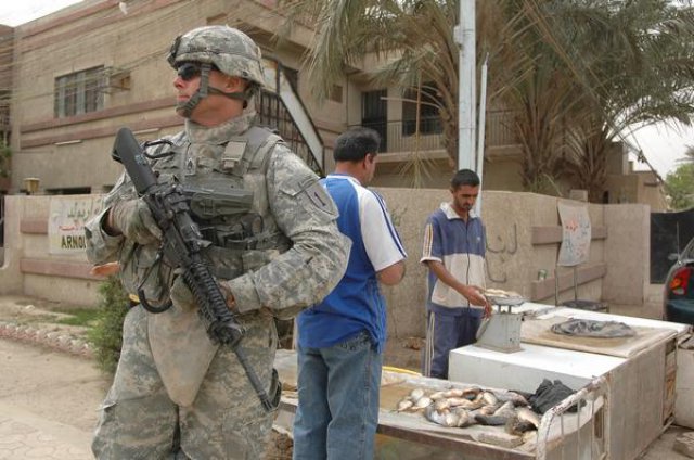 Soldier of the 1st Infantry Division stands guard in Iraqi marketplace in 2011. (Courtesy)